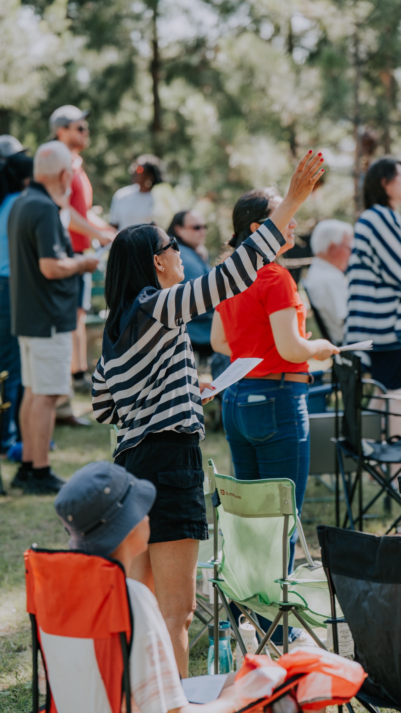 Someone worshipping with a raised hand at an outdoor Miramichi gathering