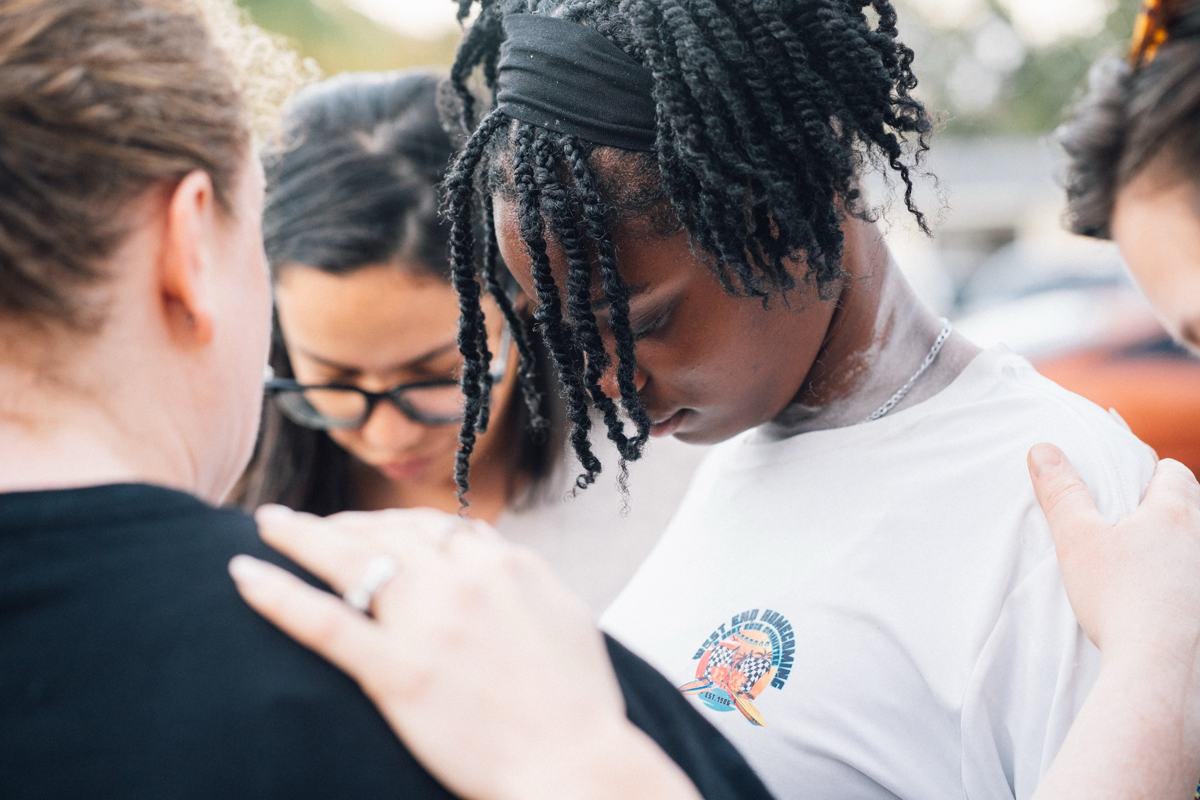 People praying together, one with a hand on another's shoulder